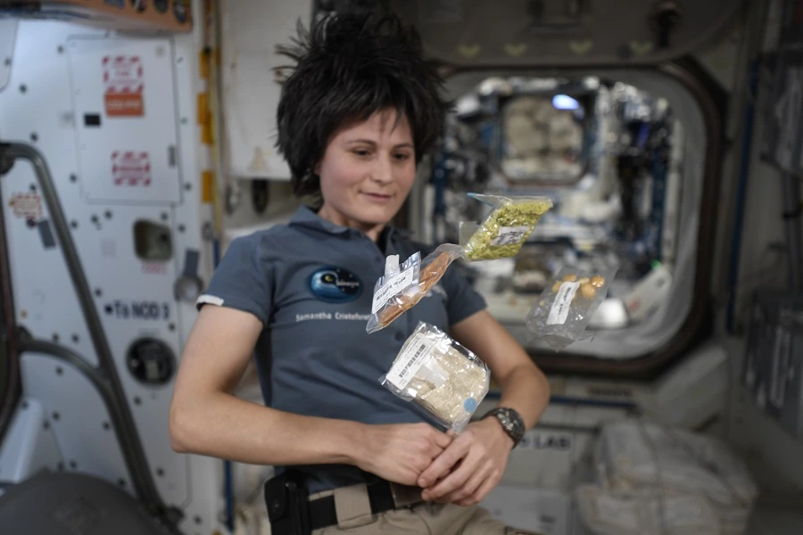 female astronaut inside ISS with floating cereal bars